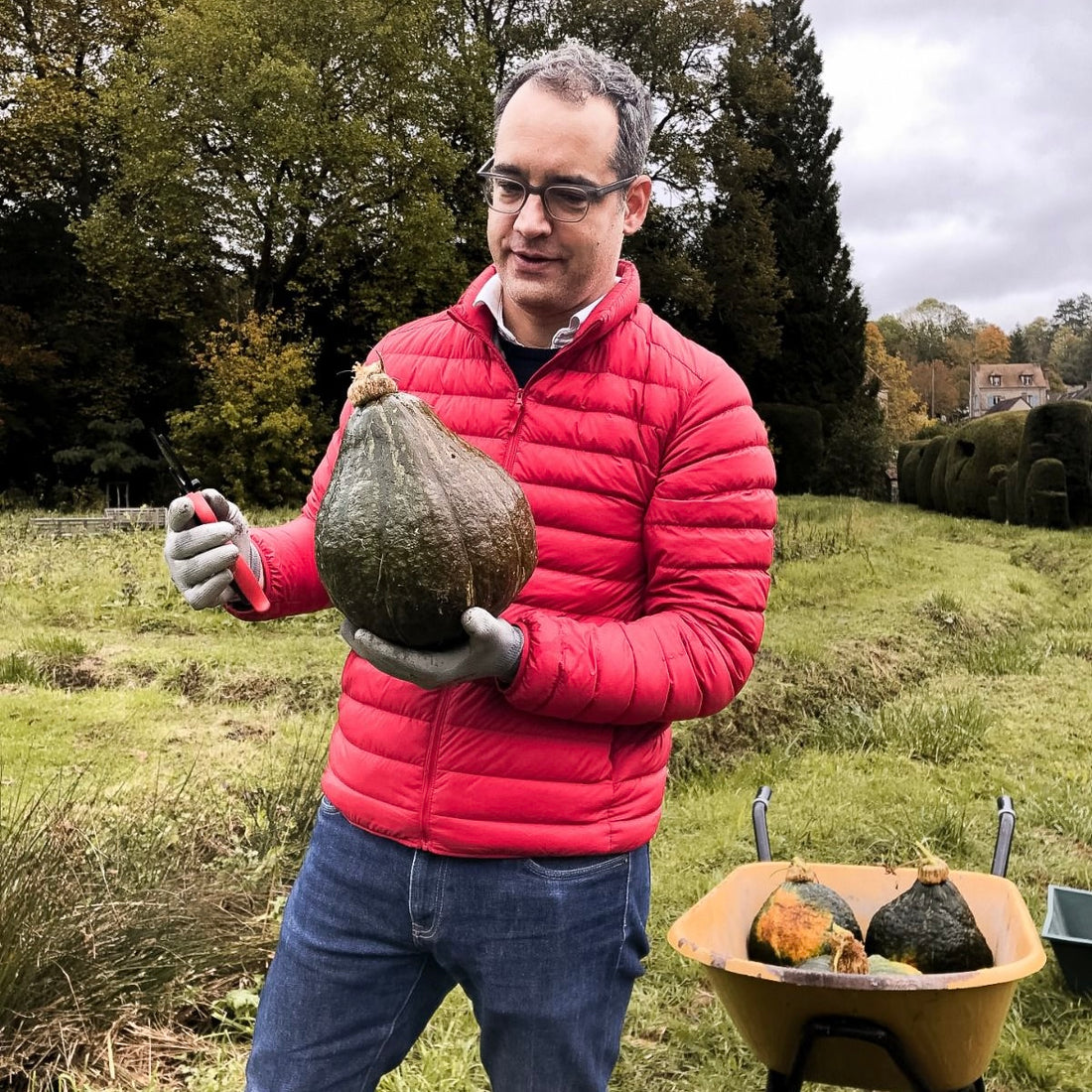 Alexander Paseau, wearing a red jacket, holding a squash pumpkin.