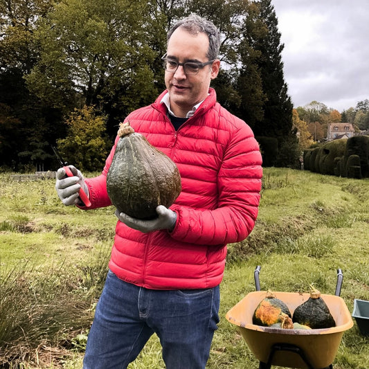 Alexander Paseau, wearing a red jacket, holding a squash pumpkin.